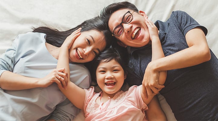 Happy-Asian-family-laying-on-bed-in-bedroom