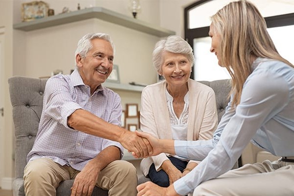 Two seniors shaking hands with an office worker